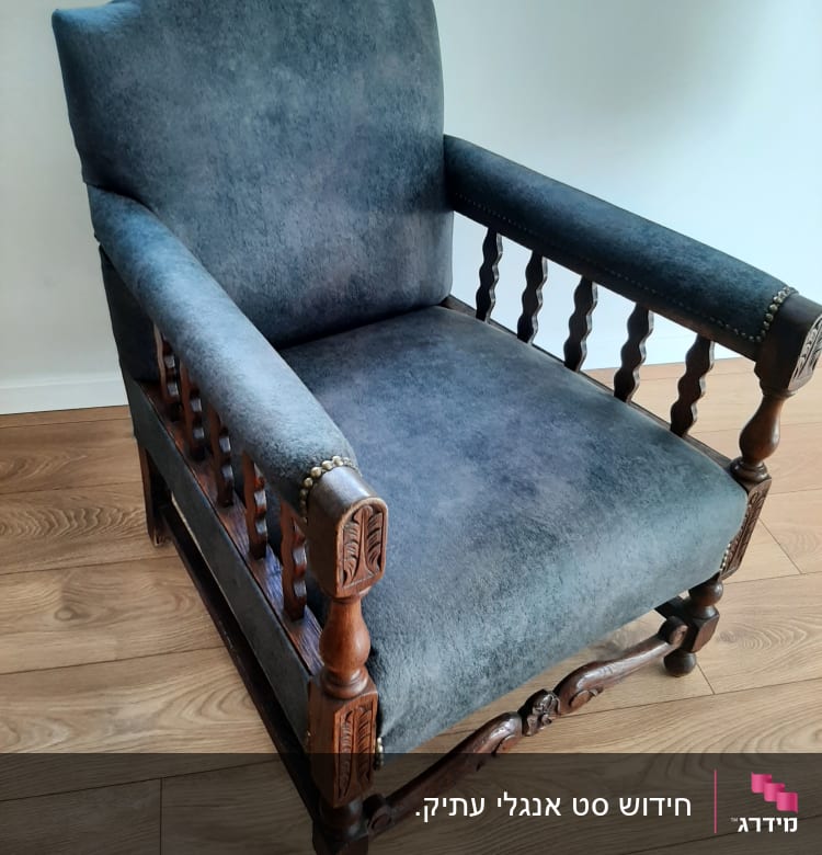 כורסה מרופדת בבד אפור עם מסגרת עץ מעוטרת